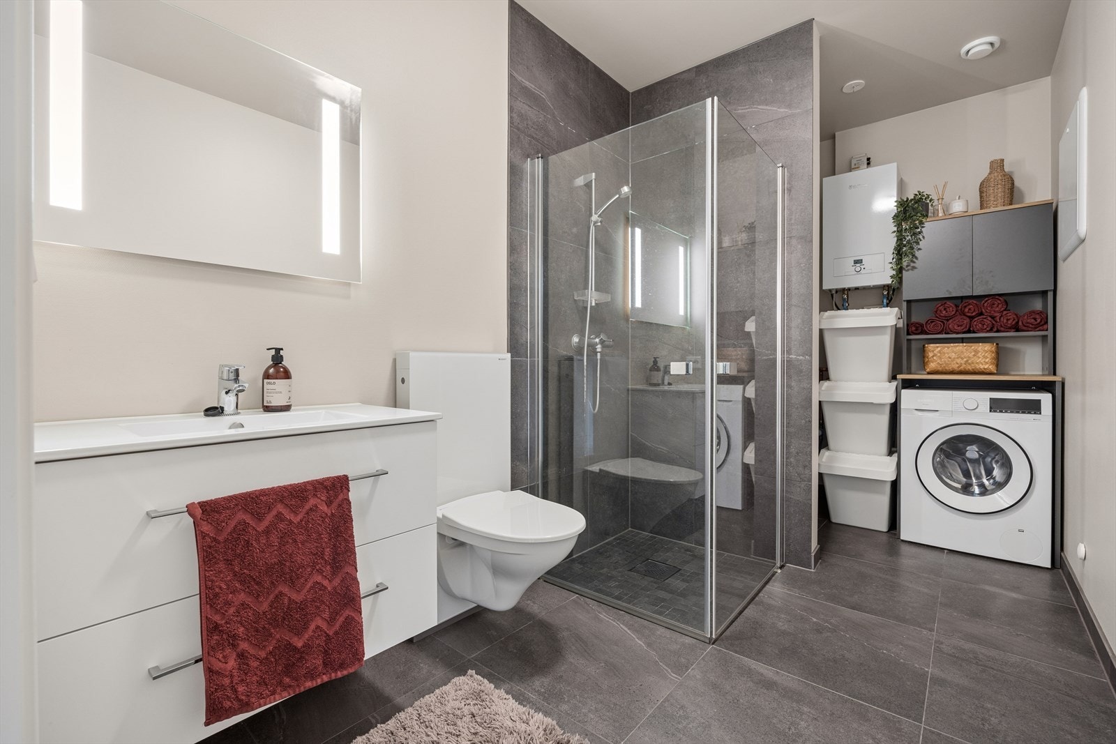 Badet har en praktisk utforming med bad og vaskerom samlet i samme rom. En halvskillevegg bidrar til å skille badesonen fra vaskeromsdelen. Galleribilde