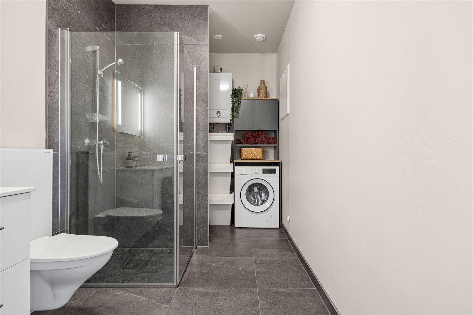 Badet har fliser på gulvet og i dusjsonen. Mosaikkflisene i dusjen er kombinert med flislister i samme utførelse, noe som bidrar til et moderne preg. Galleribilde