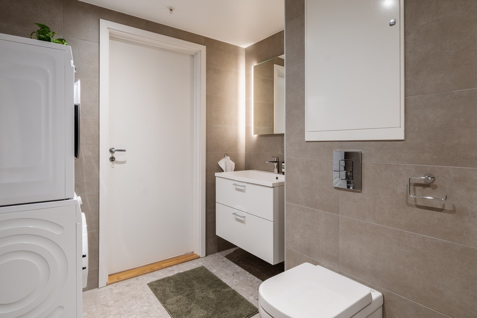 Videre er badet innredet med baderomsinnredning med skuffer, vegghengt speil og vegghengt toalett. Galleribilde