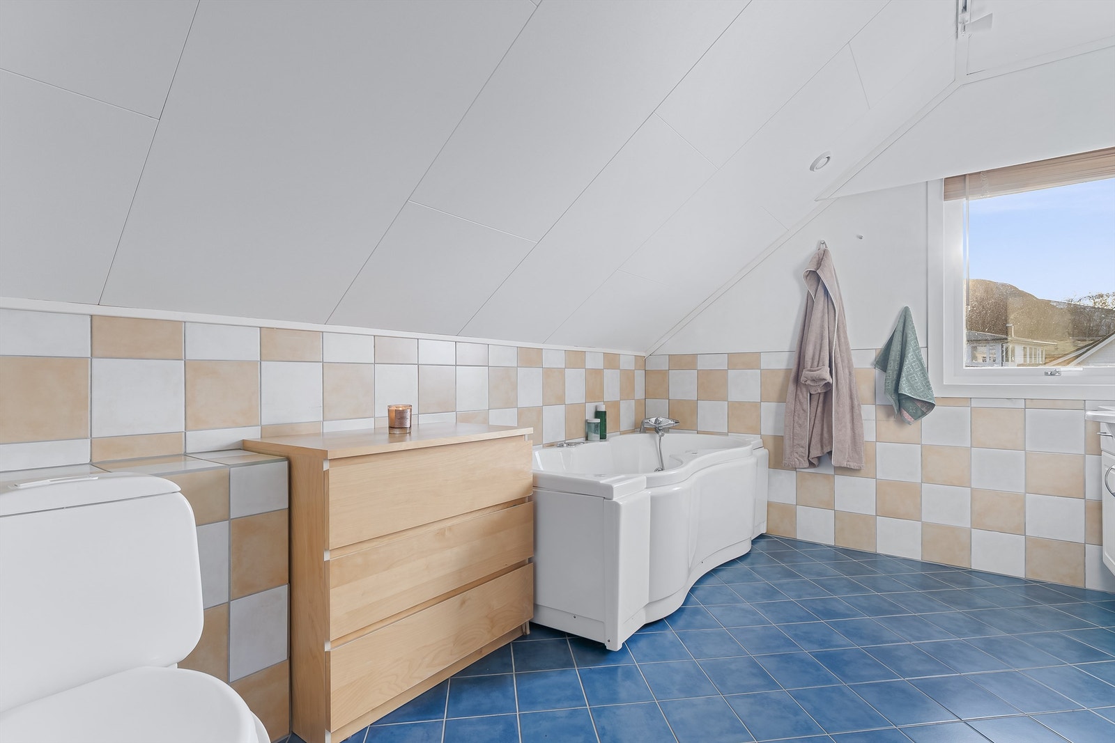 Badet er utstyrt med baderomsinnredning, boblebadekar og gulvmontert toalett Galleribilde