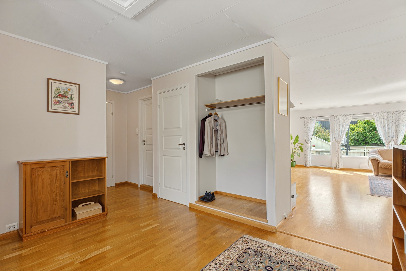 Velkommen inn! En lys og innbydende entré med praktisk garderobeløsning og en åpen forbindelse til boligens oppholdsrom. Galleribilde