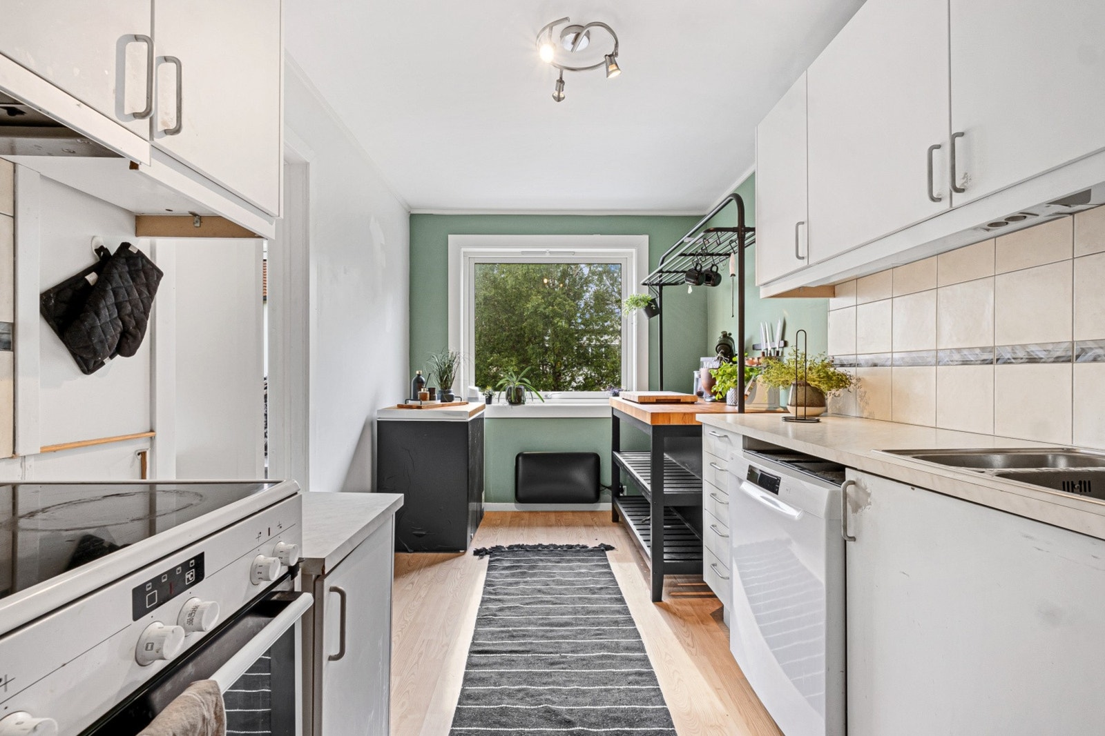 Kjøkkeninnredning med hvite, slette fronter og laminat benkeplate. Galleribilde