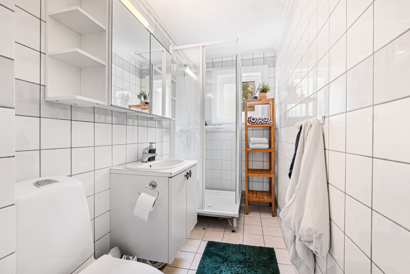 Helfliset bad utstyrt med dusjkabinett, servant med underskap og toalett. Galleribilde