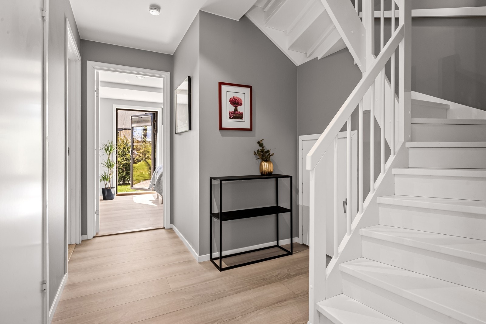 Hallen i første etasje har en malt tretrapp og fordeler tilgang til etasjens tre soverom og stue. Plassen under trappen er praktisk utnyttet som bodrom. Galleribilde