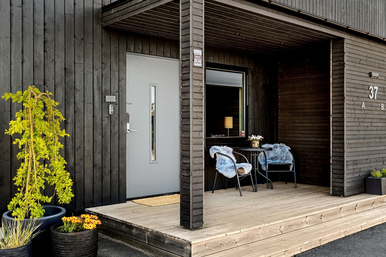 Overbygget, innbydende inngangsparti og fasade med stående bordkledning. Her er det plass til en koselig café-sett. Galleribilde