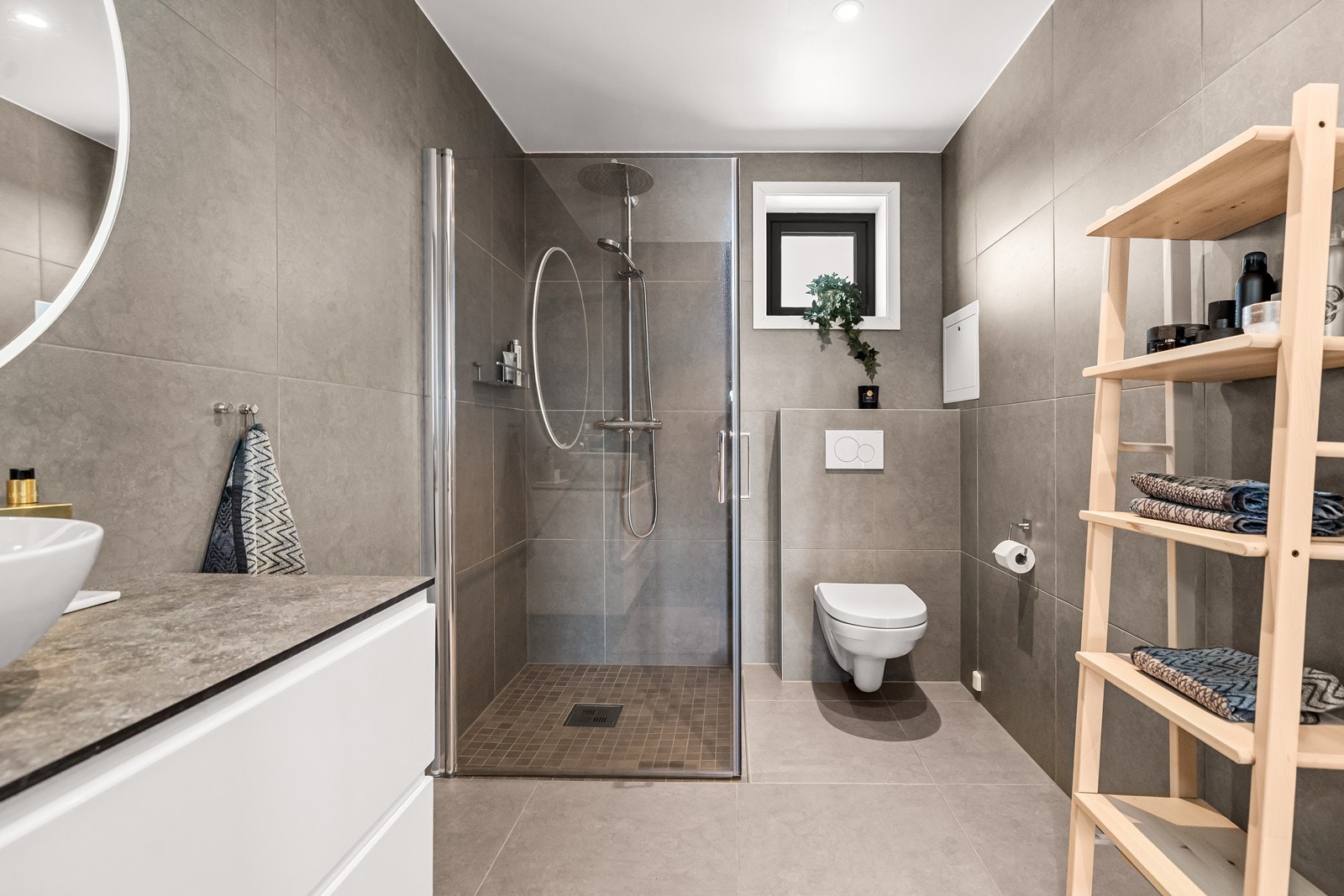 Badet i andre etasje har et innbydende uttrykk, med tidsriktige flislagte overflater. I gulvet er det elektriske varmekabler. Rommet er innredet med dusjhjørne med glassvegger, og veggmontert wc. Galleribilde