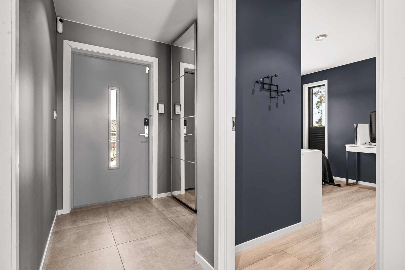 Entréen har flislagt gulv og gir adkomst til hall med trapp til andre etasje. Inngangsdøren har installert en Yale elektrisk smartlås. I Entréen er det dessuten plass til gardeobeskap for lagring av yttertøy. Galleribilde