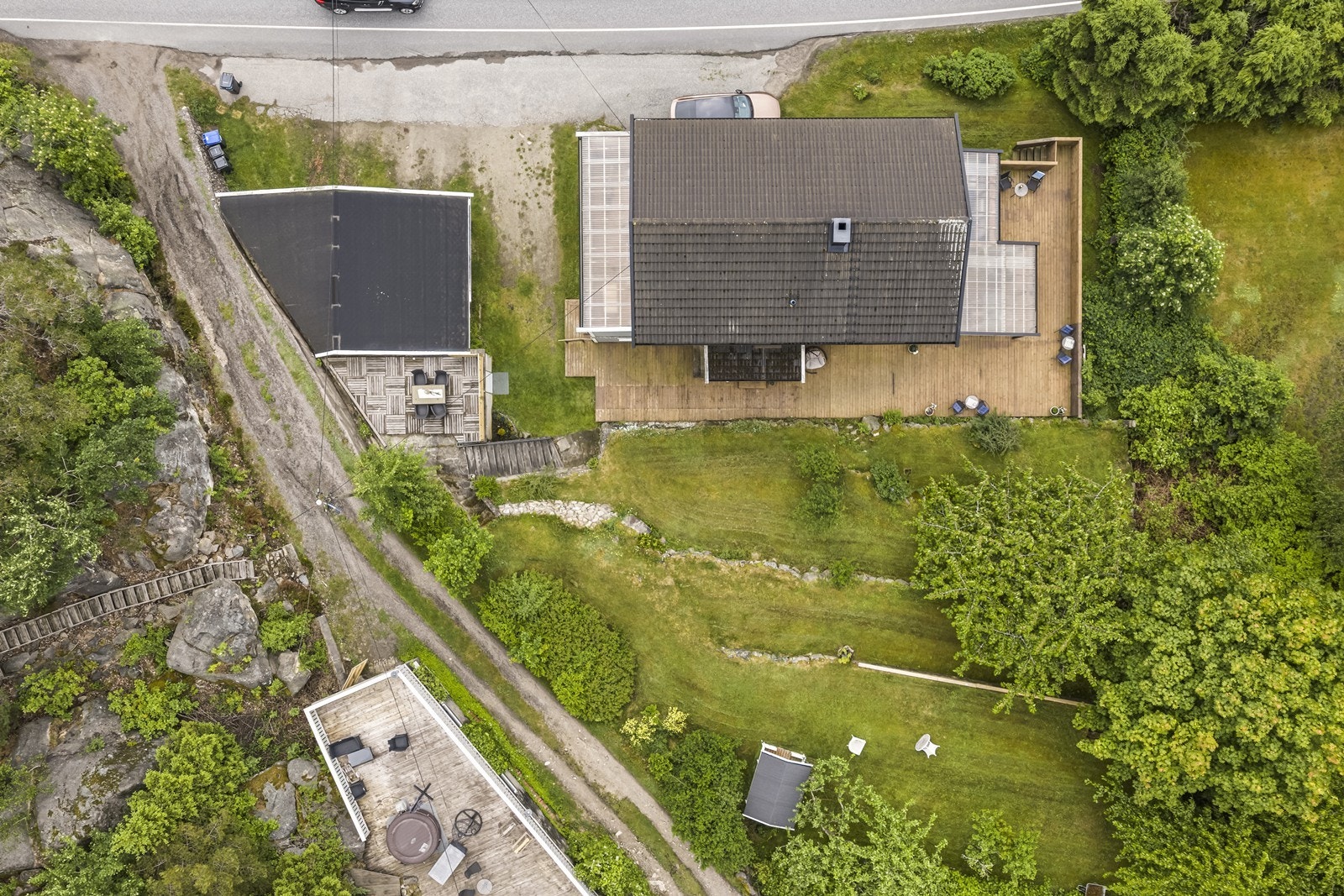 Tomten er opparbeidet med asfaltert og gruset gårdsplass, plen og terrasser. Galleribilde