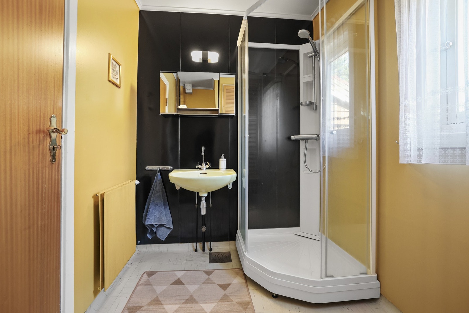 Bad utstyrt med servant, dusjkabinett og radiator. Galleribilde