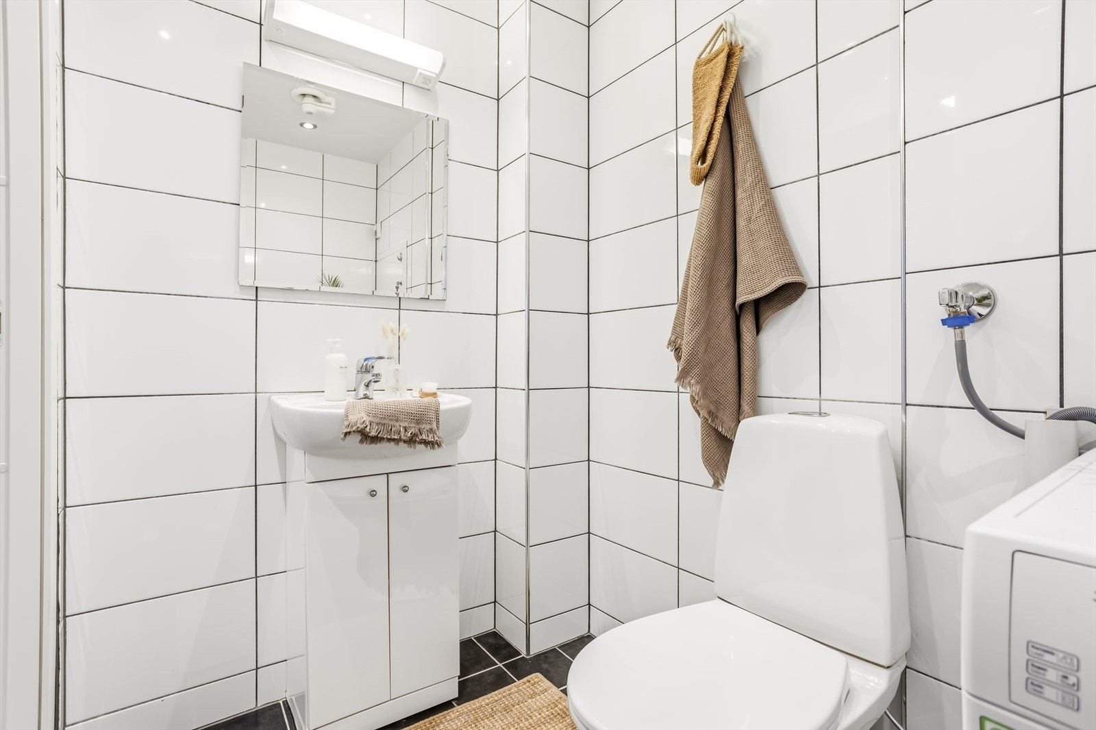 Videre er det innredet med gulvstående toalett, servant med skap og opplegg for vaskemaskin. Galleribilde
