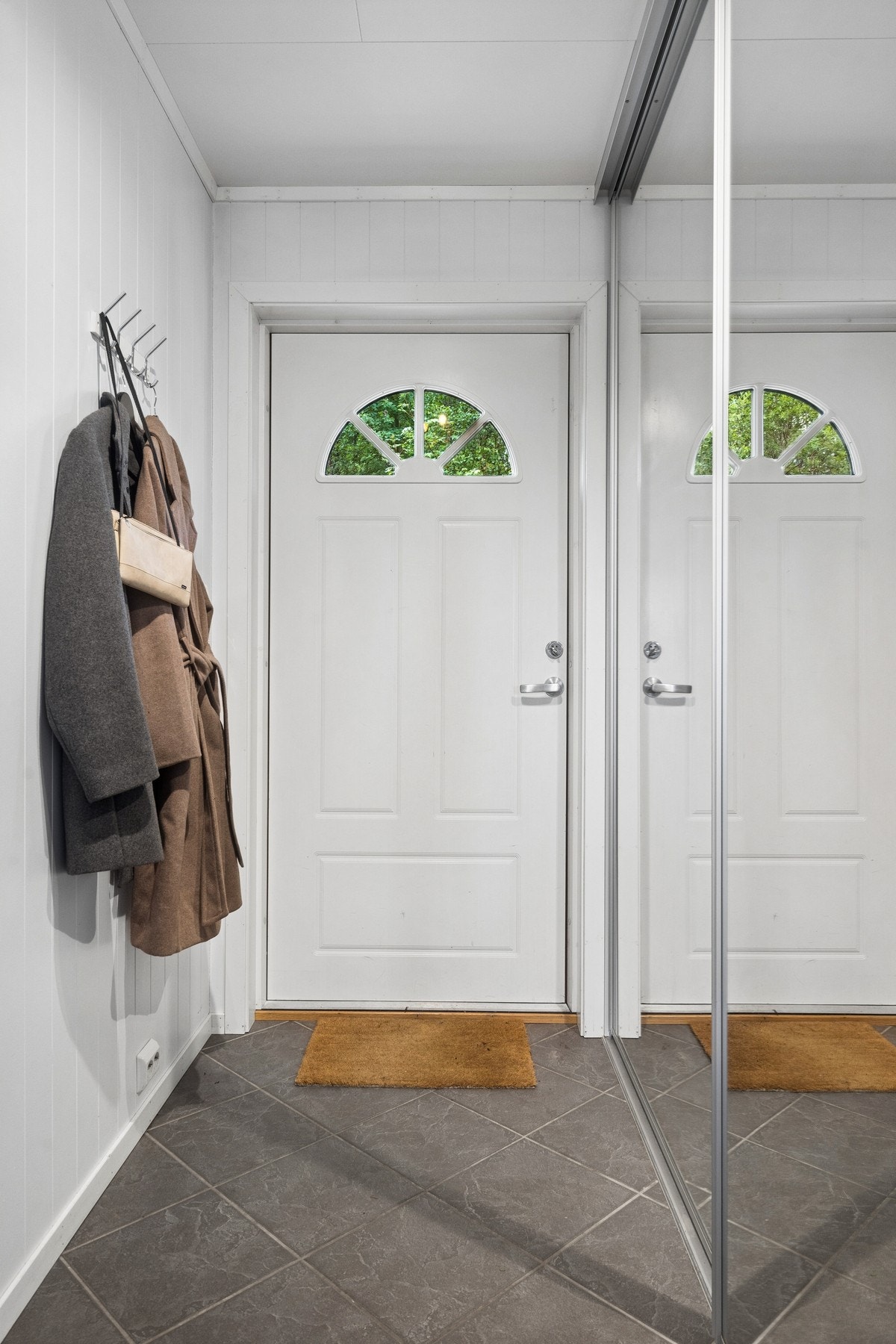 Entré med flislagt gulv og skyvedørsgarderobe med speilfronter. Galleribilde