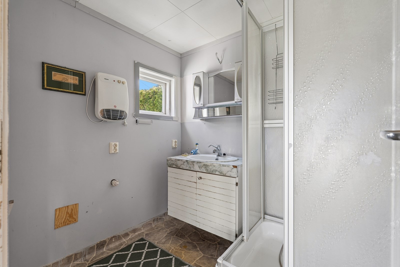Badet er innredet med dusjkabinett og servant med underskap og speil. Galleribilde