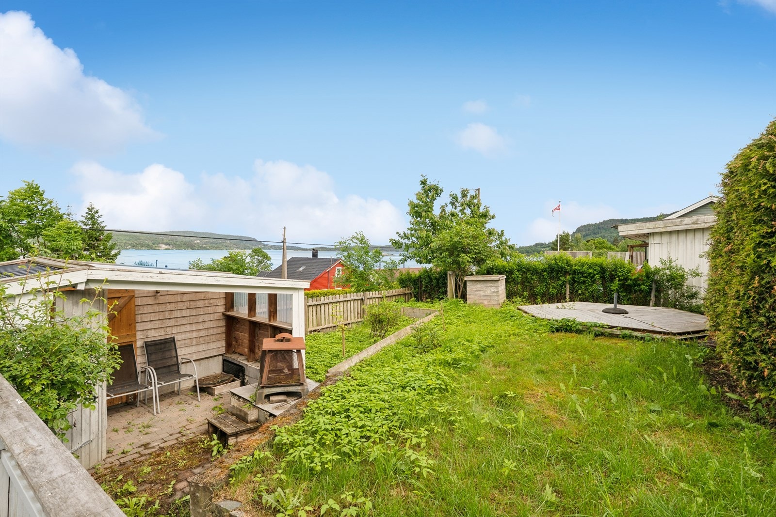 Tomten er tidligere opparbeidet med hekk, gressplen, terrasse, platting, blomsterbed og utekjøkken. Galleribilde