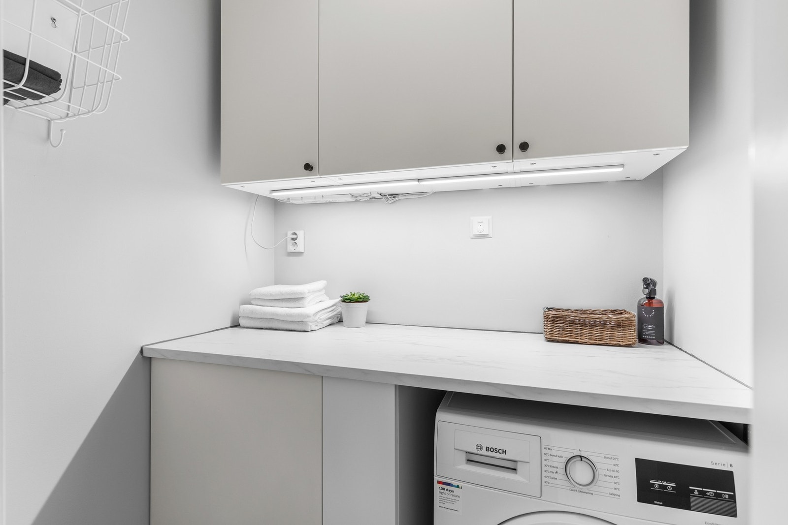 Eget vaskerom er en kvalitet mange setter pris på i hverdagen. Her er god oppbevaringsplass i skap, samt praktisk benkeplass for bretting og sortering av klesvask. Galleribilde