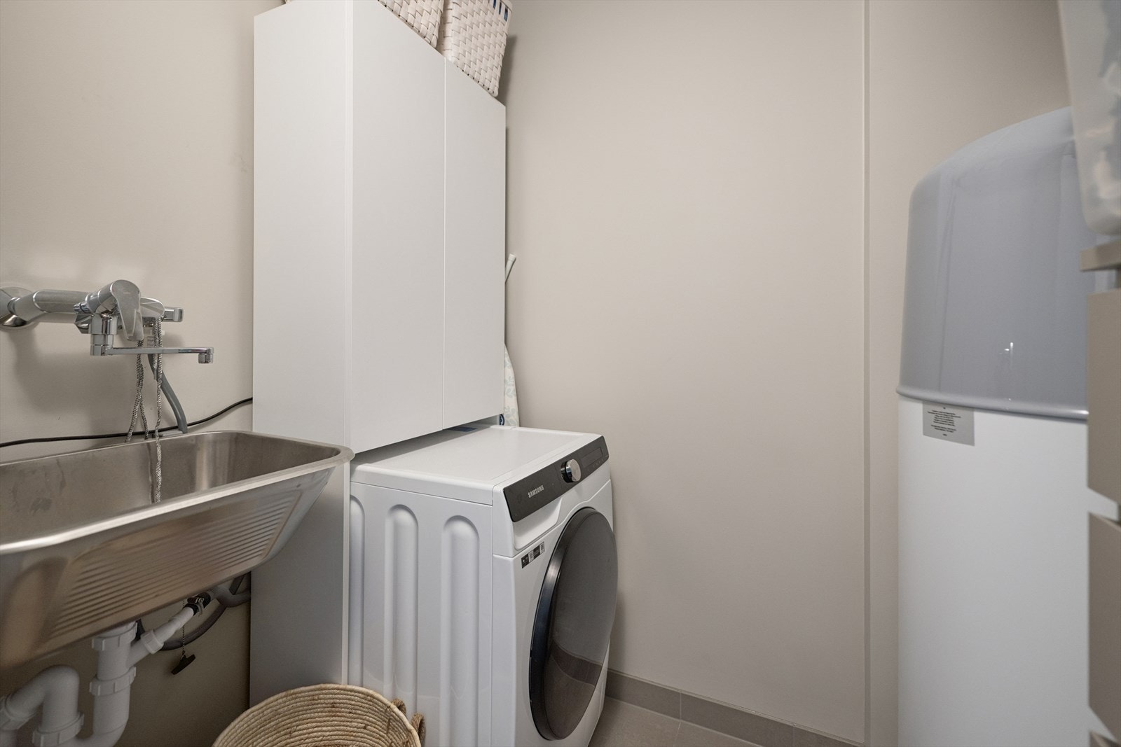 Romslig vaskerom med plass til vaskemaskin , tørketrommel og oppbevaring. Galleribilde