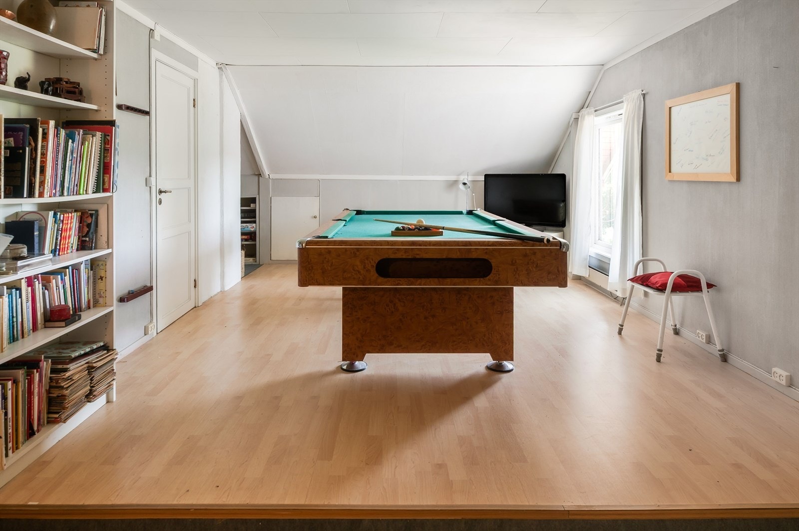 Loftstuen er i dag innredet med et biljardbord og bokhyller. Galleribilde
