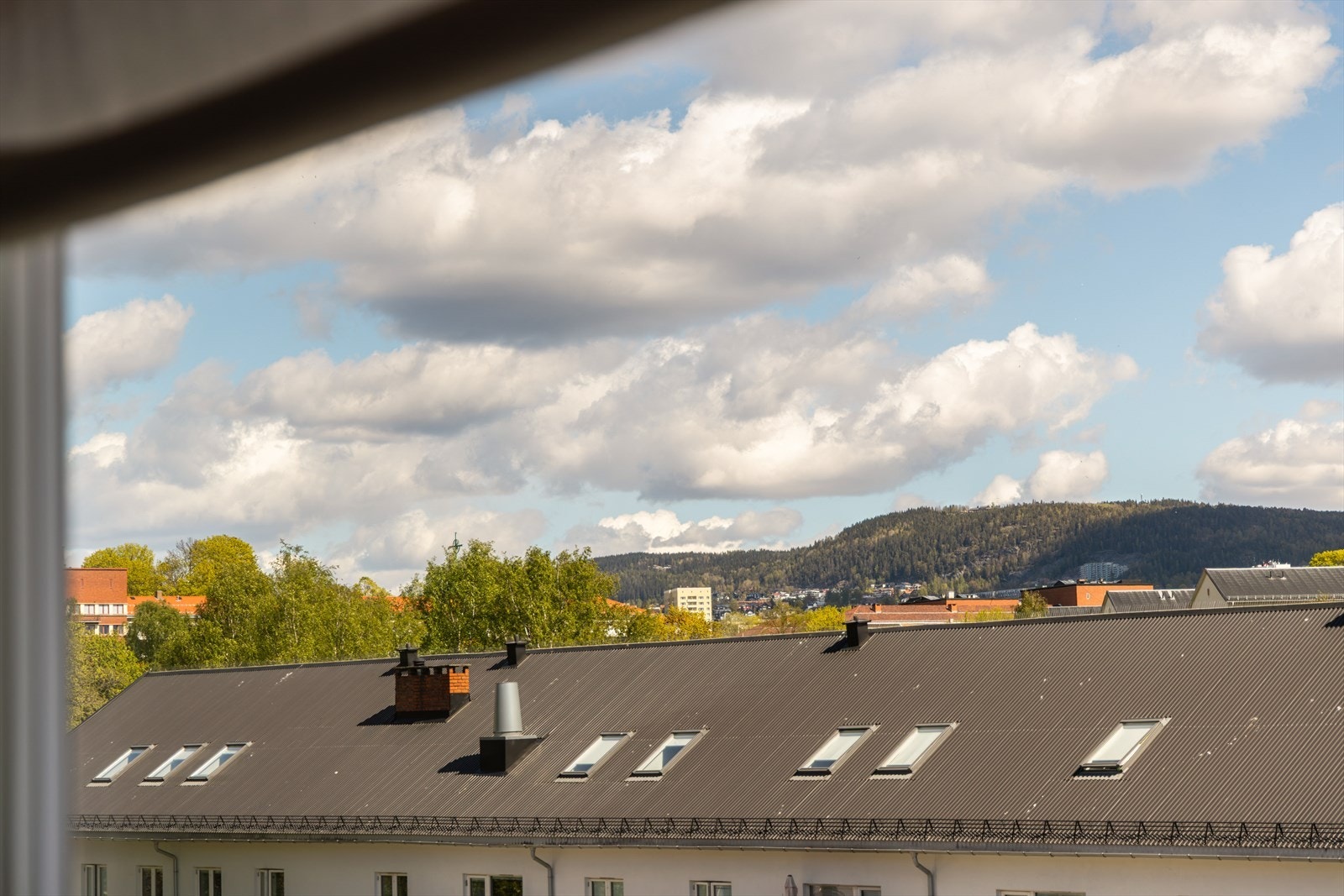 Det store vinduet slipper inn godt med naturlig lys og byr på en hyggelig utsikt mot nærmiljø og de grønne åsene rundt Galleribilde