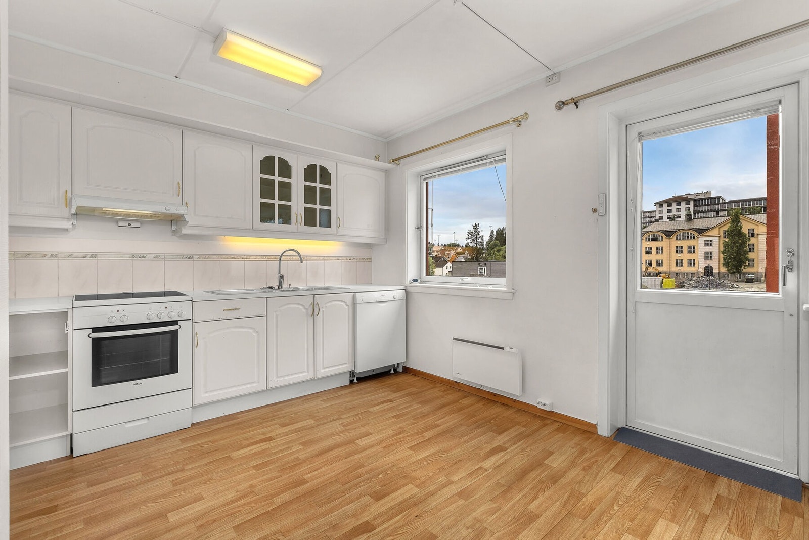 Kjøkkeninnredning fra byggeåret med lyse, profilerte fronter og laminatbenkeplate. Galleribilde