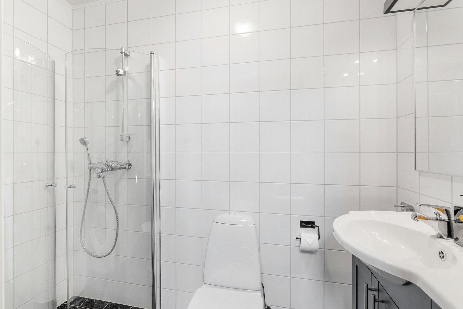 Badet i første etasje har flislagte overflater, servant, dusjhjørne og varmekabler i gulv. Galleribilde