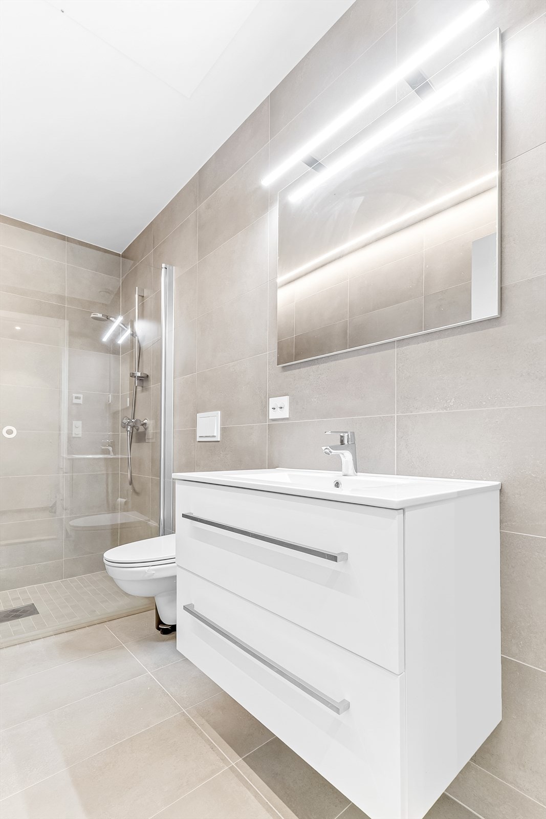 Badet inneholder dusj, servant og vegghengt toalett. Galleribilde