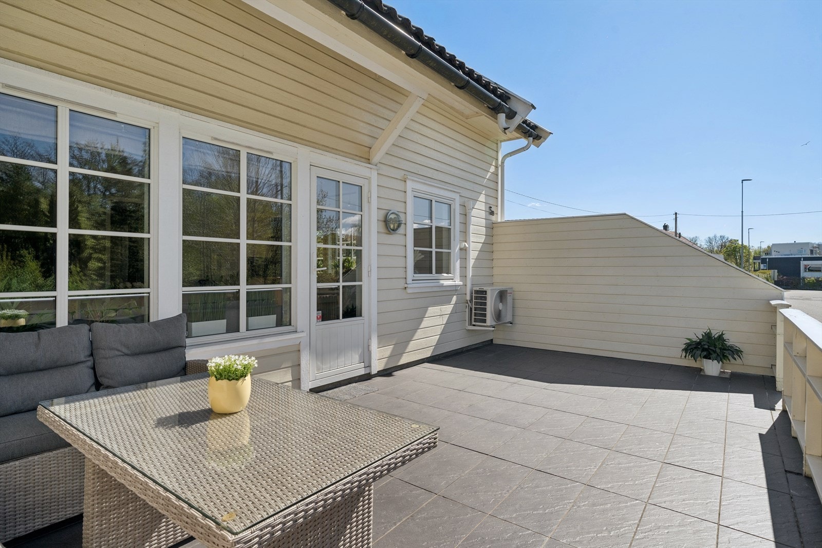 Romslig og solrik terrasse med skiferfliser, som gir et stilrent og vedlikeholdsvennlig uterom. Store vindusflater og terrassedør gir god sammenheng mellom inne og uteområde. Galleribilde