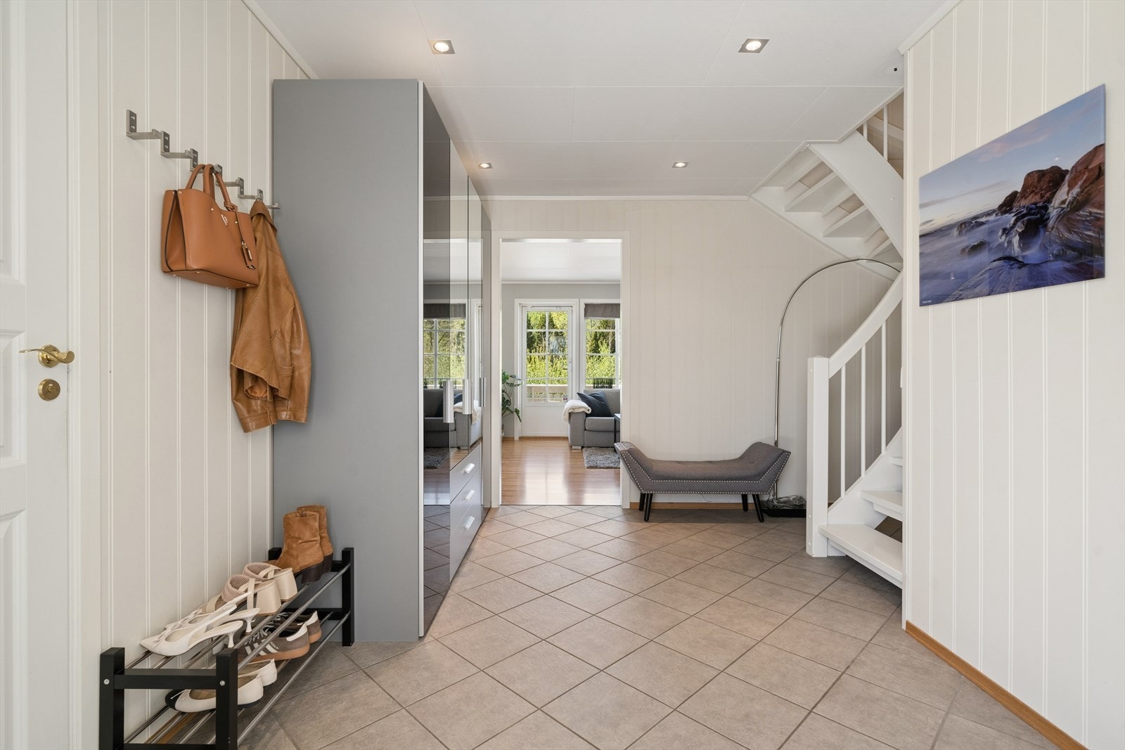 Romslig og innbydende hall med god plass til oppbevaring av yttertøy og sko. Flislagt gulv gir en slitesterk og praktisk løsning, mens lyse vegger og downlights i himling skaper et moderne og velkommende uttrykk. Vaskerom med WC inn døren til venstre. Galleribilde