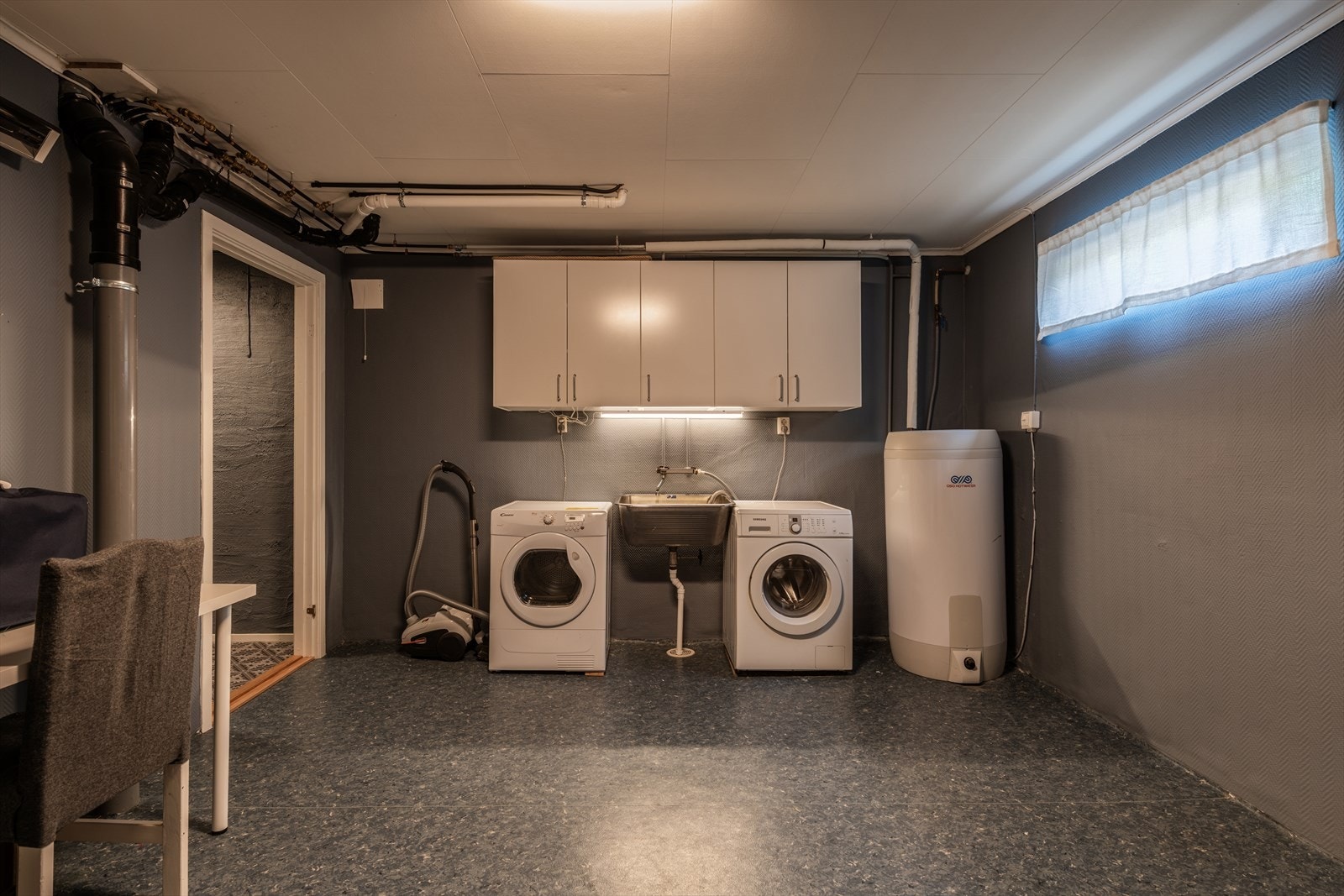 Romslig vaskerom med opplegg for vaskemaskin og en 200-liters varmtvannsbereder fra 2020. Galleribilde