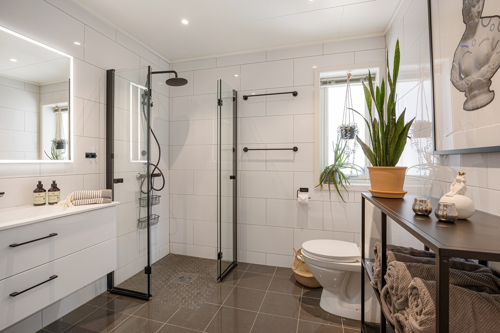 Badet har dusjhjørne med regnfalls- og hånddusj og foldedører av glass. Toalettet er gulvstående og i gulvet er det behagelig varme. Galleribilde