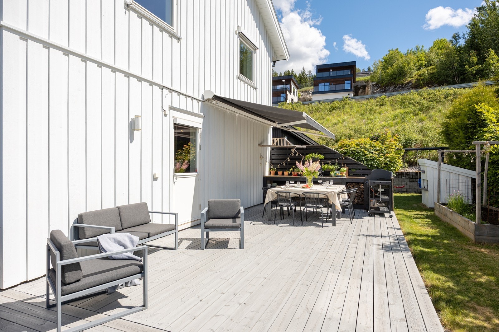 Terrassen strekker seg langs to sider av boligen - noe som gjør det enkelt å følge solen gjennom dagen. Deler av terrassen er overbygd, mens andre soner har markise for effektiv solskjerming de varmeste dagene. Galleribilde