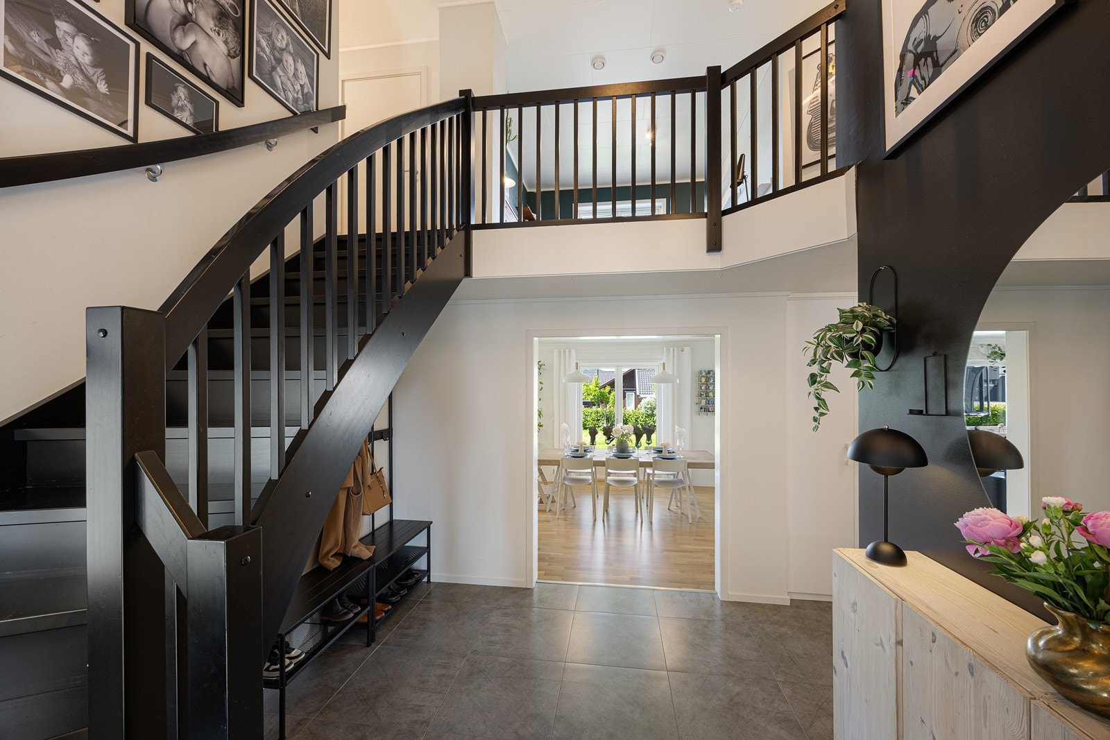 Hallen har glatte vegger i en lys fargetone med mørke fondvegger,
og under det flislagte gulvet er det lun varme. En bred døråpning fører inn til stuen. Galleribilde