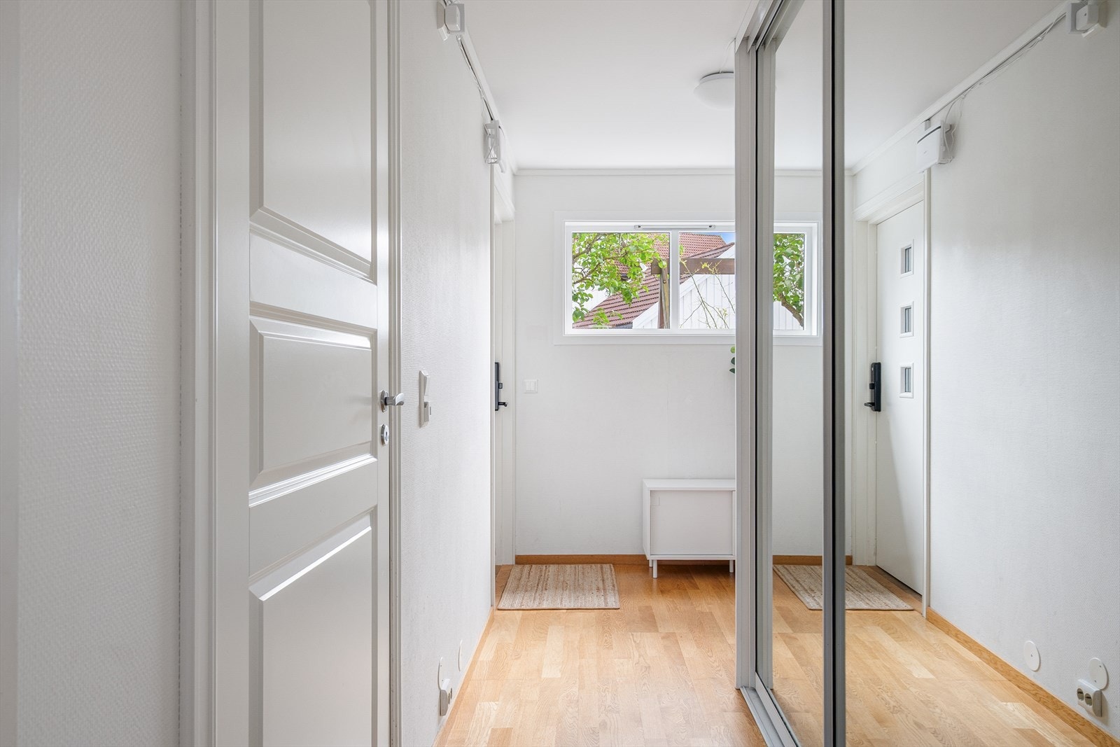 Lys entré med parkett på gulv og plass til oppbevaring i skyvedørsgarderobe. Galleribilde