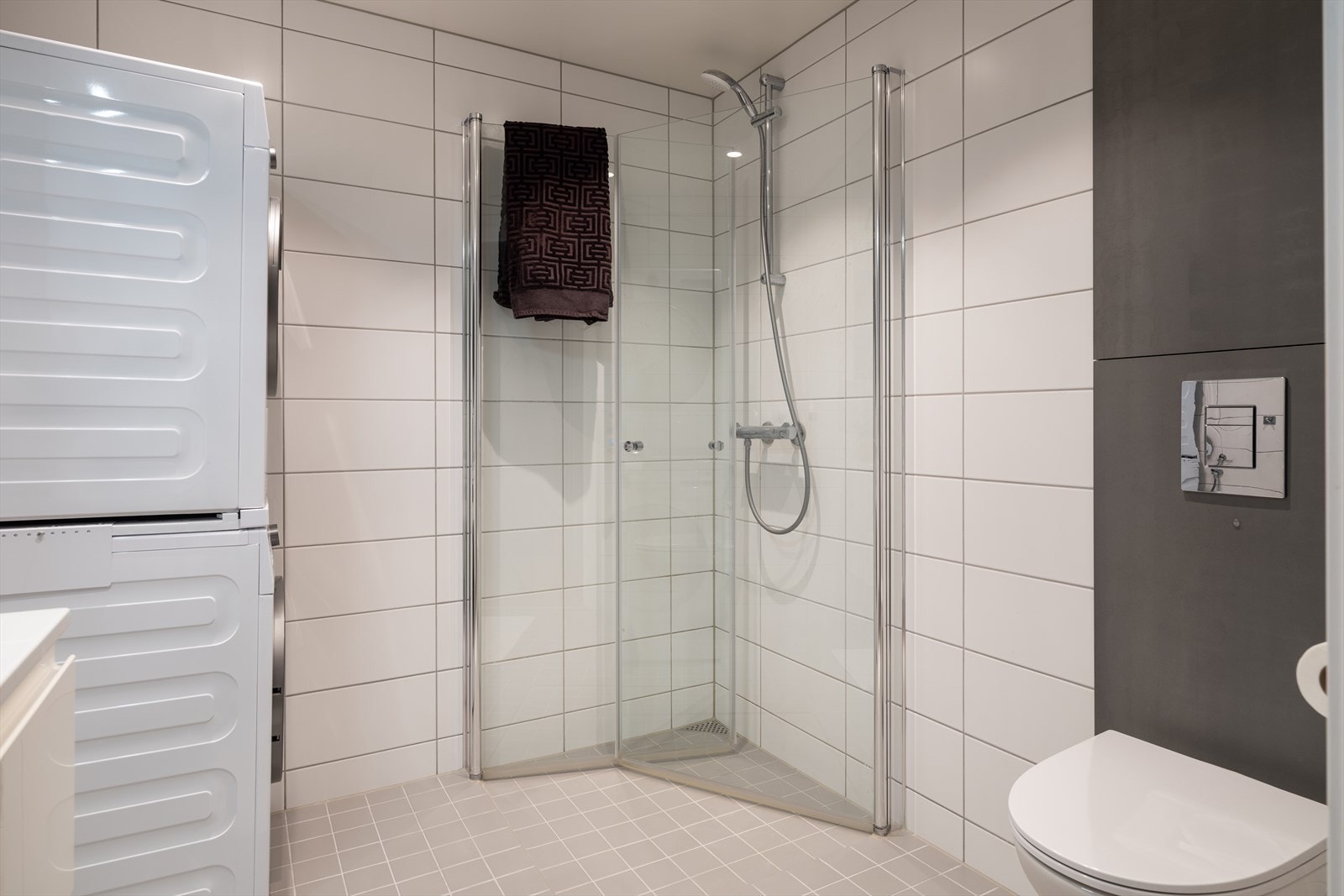 Badet byr på servant, servantskap, innfellbare dusjsdører, veggmontert wc og opplegg for vaskemaskin. Galleribilde