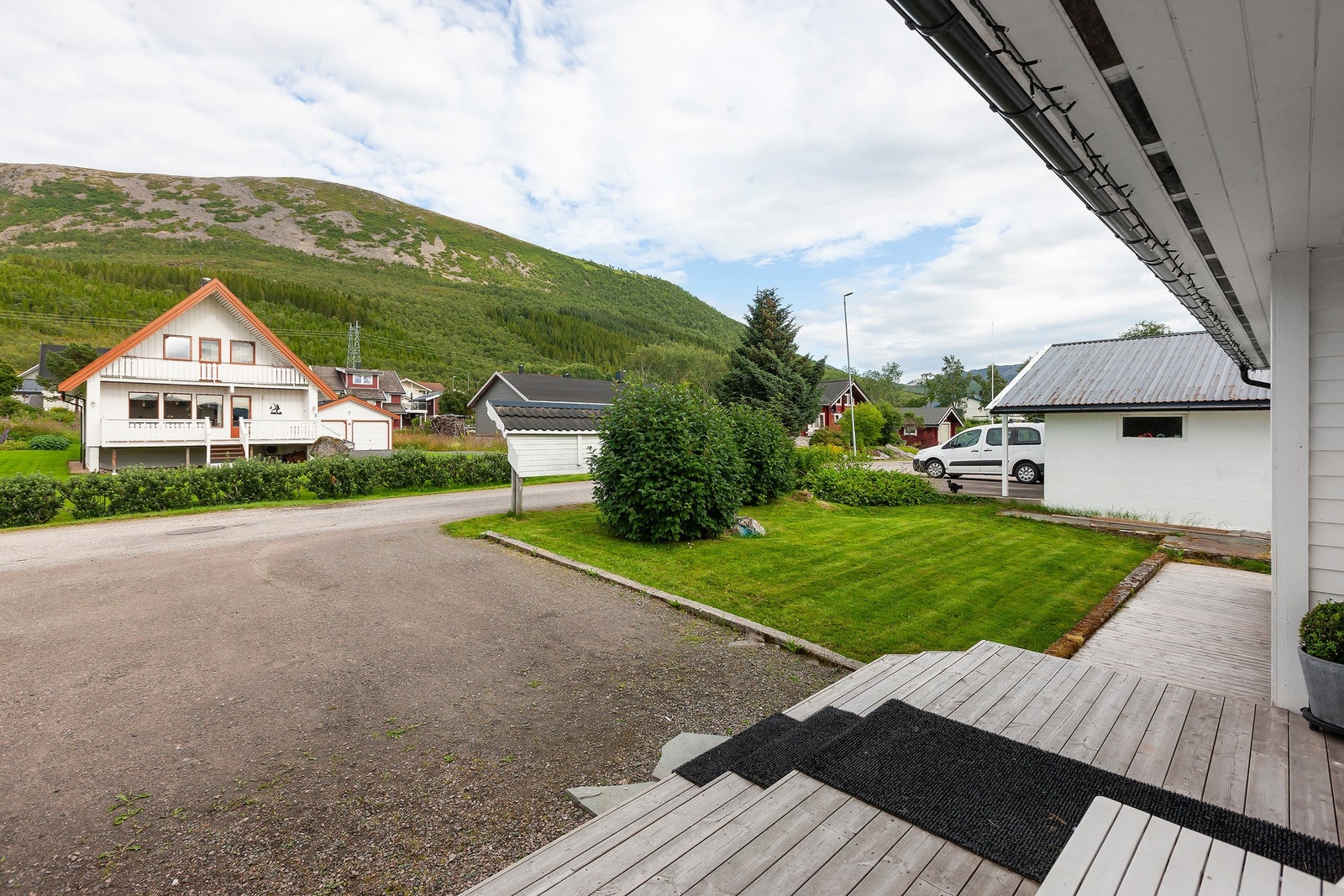 Utsyn fra inngangspartiet mot nærområdet, hage og fjell. Galleribilde