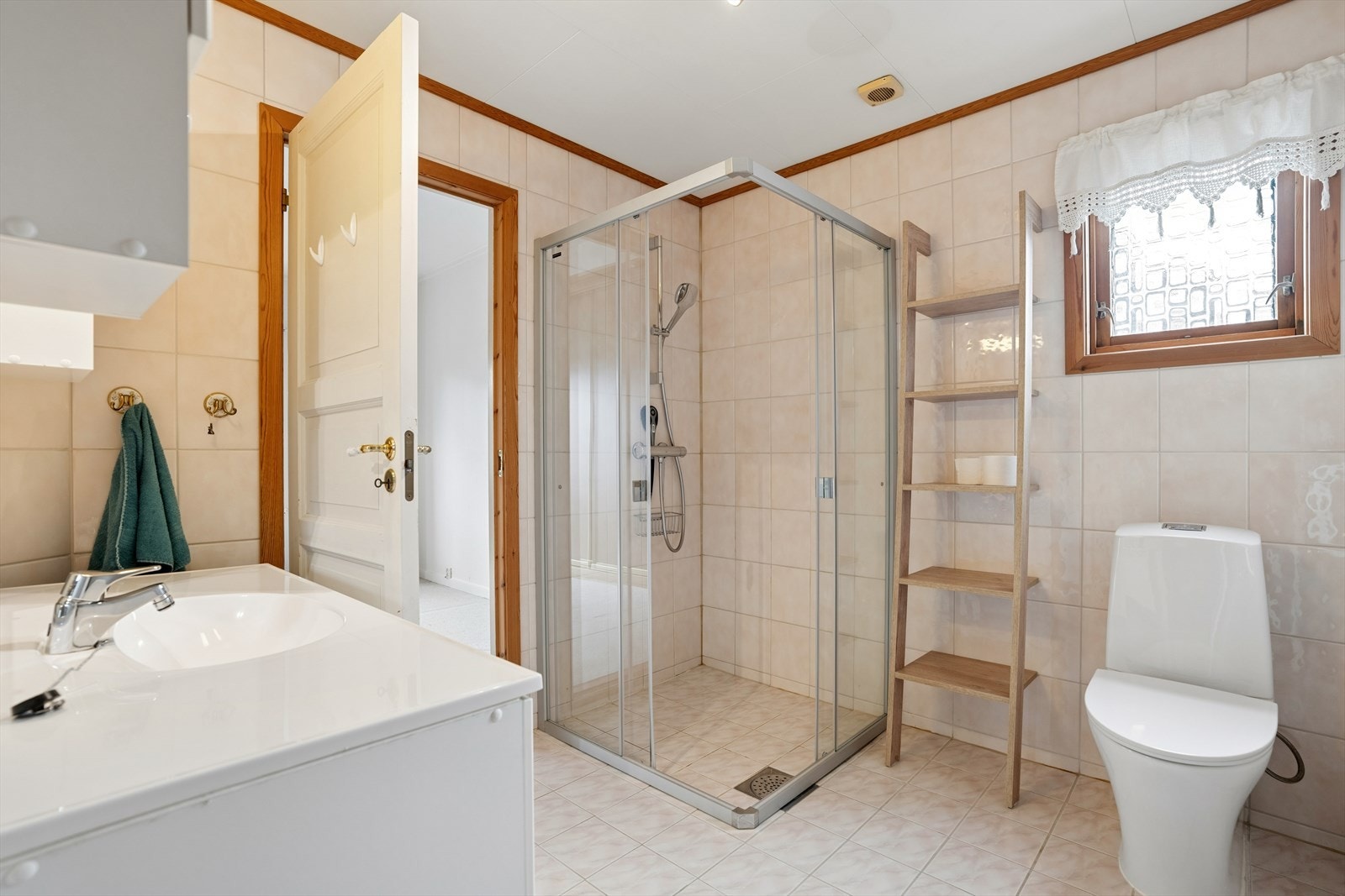 Badet i hovedetasjen har flislagt gulv med varmekabler og en dusjnisje med glassdører. Galleribilde