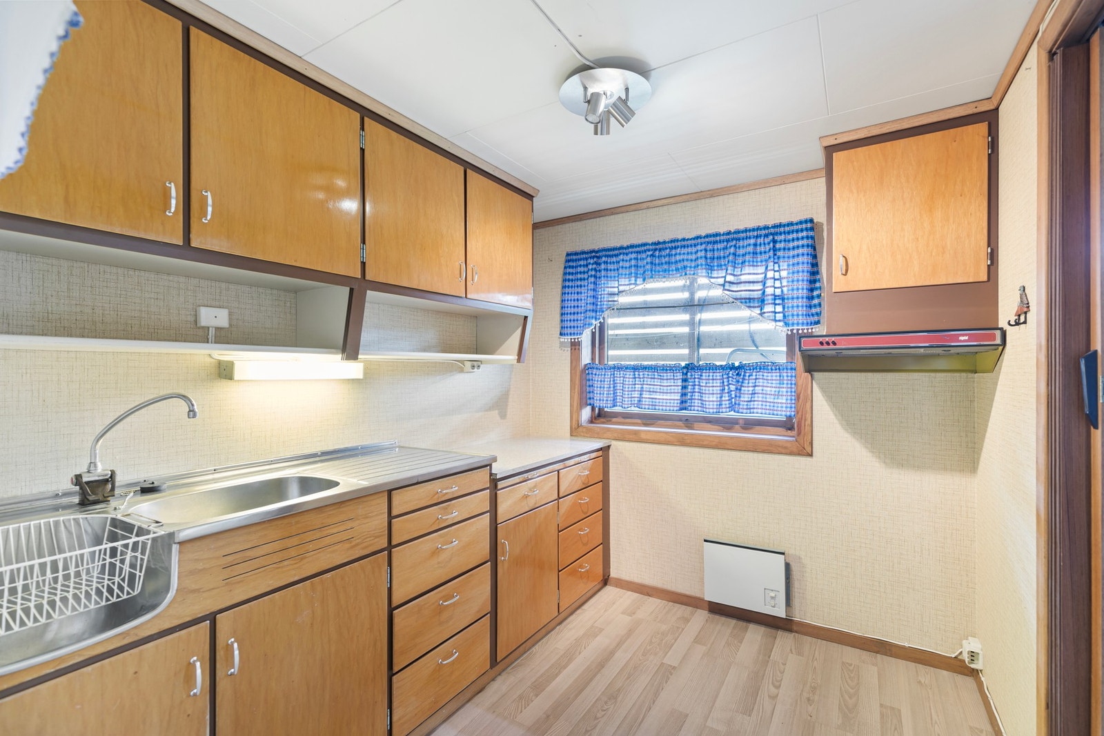 Enkel kjøkkeninnredning med lakkerte finerte fronter. Innredningen er utstyrt med utslagsvask, oppvaskkum og ventilator. Galleribilde
