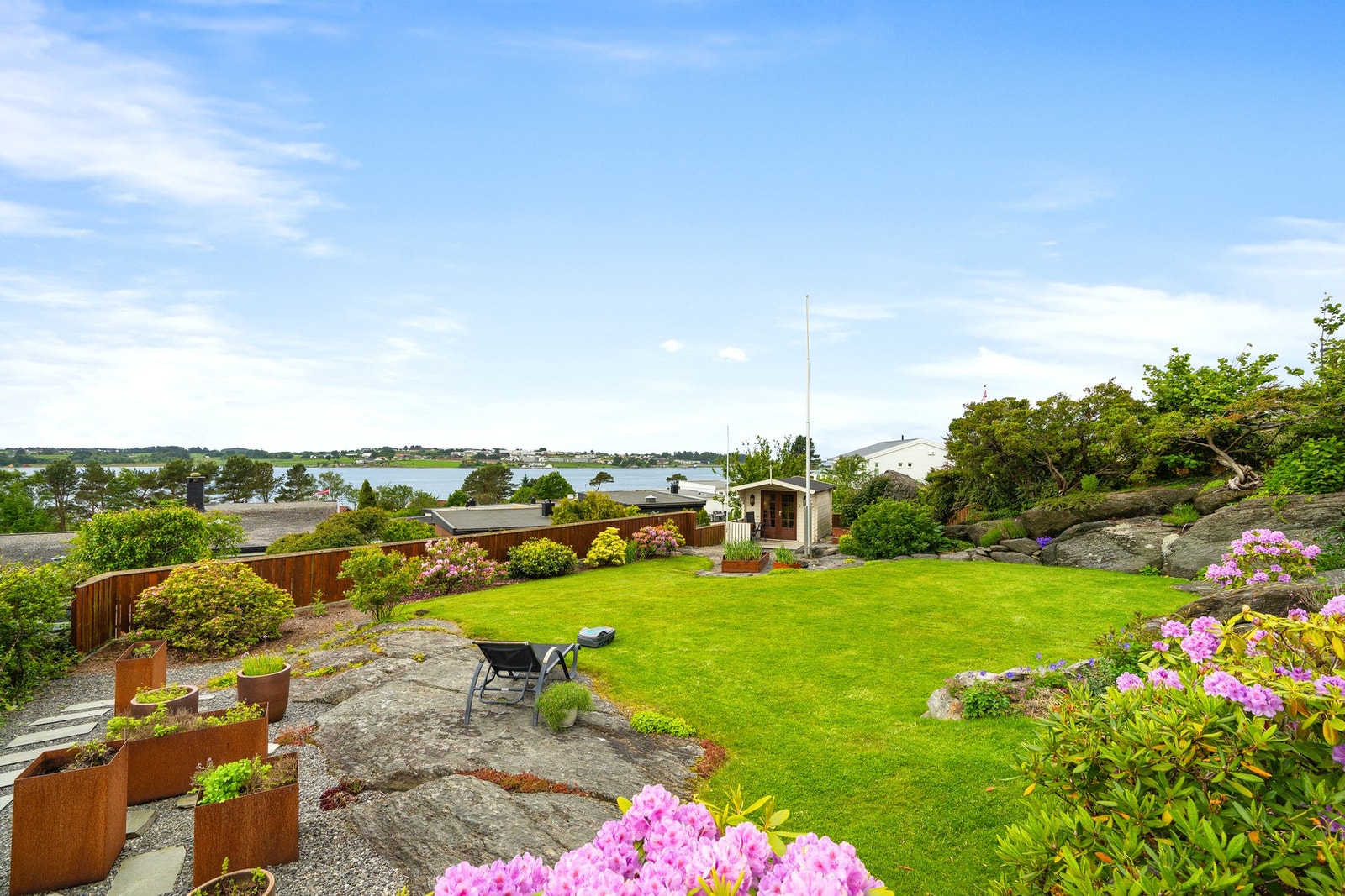Hagen i flott blomstring. Nederst i høyre bildekant ser man en enkel utebod/lekestue. Galleribilde