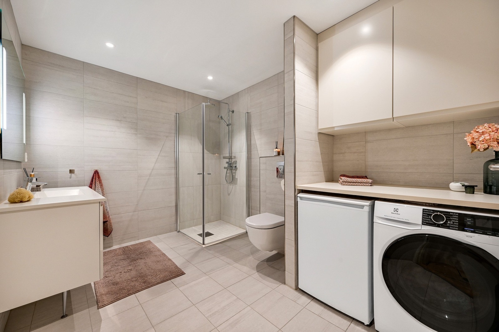 Badet er innredet med praktiske dusjvegger, pen baderomsinnredning, vegghengt klosett, samt opplegg for vaskemaskin. I tillegg er det en praktisk benk og skap på badet Galleribilde