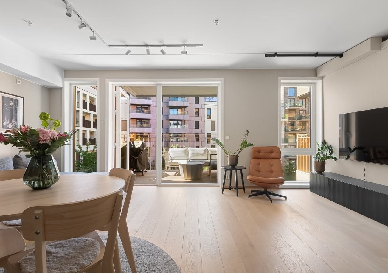 Stuen er stor og har sofa, TV og spisebord med stoler som medfølger. Galleribilde