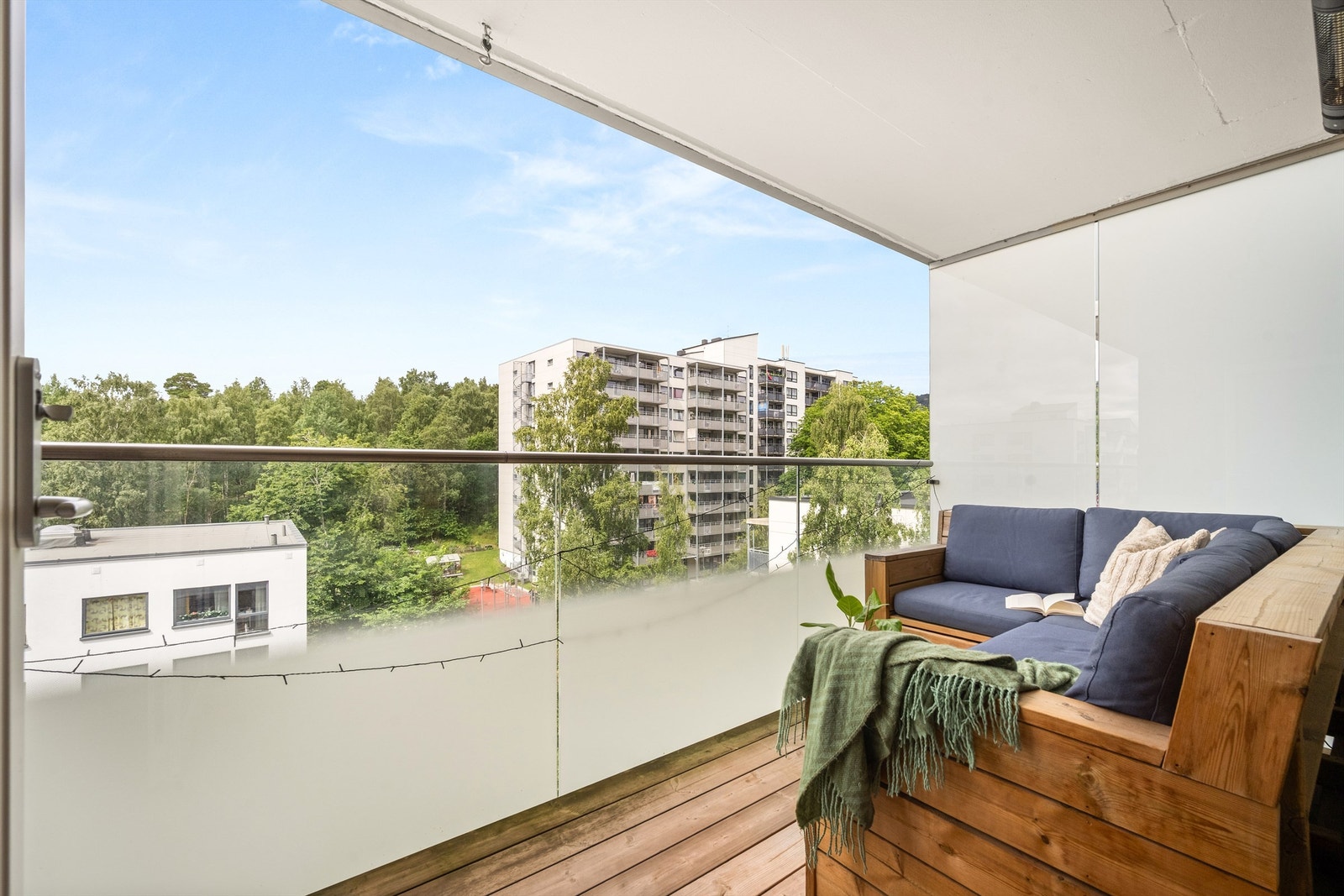 Balkongen har gulv belagt med terrassebord og et moderne rekkverk av metall og glass. Galleribilde