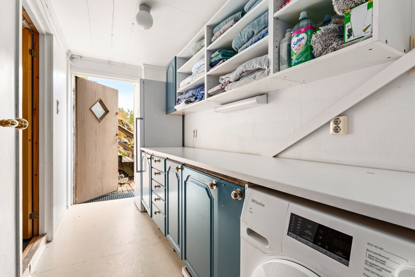 Praktisk vaskerom med god benkeplass, rikeleg oppbevaring og direkte utgang til hagen og eit teknisk rom. Galleribilde
