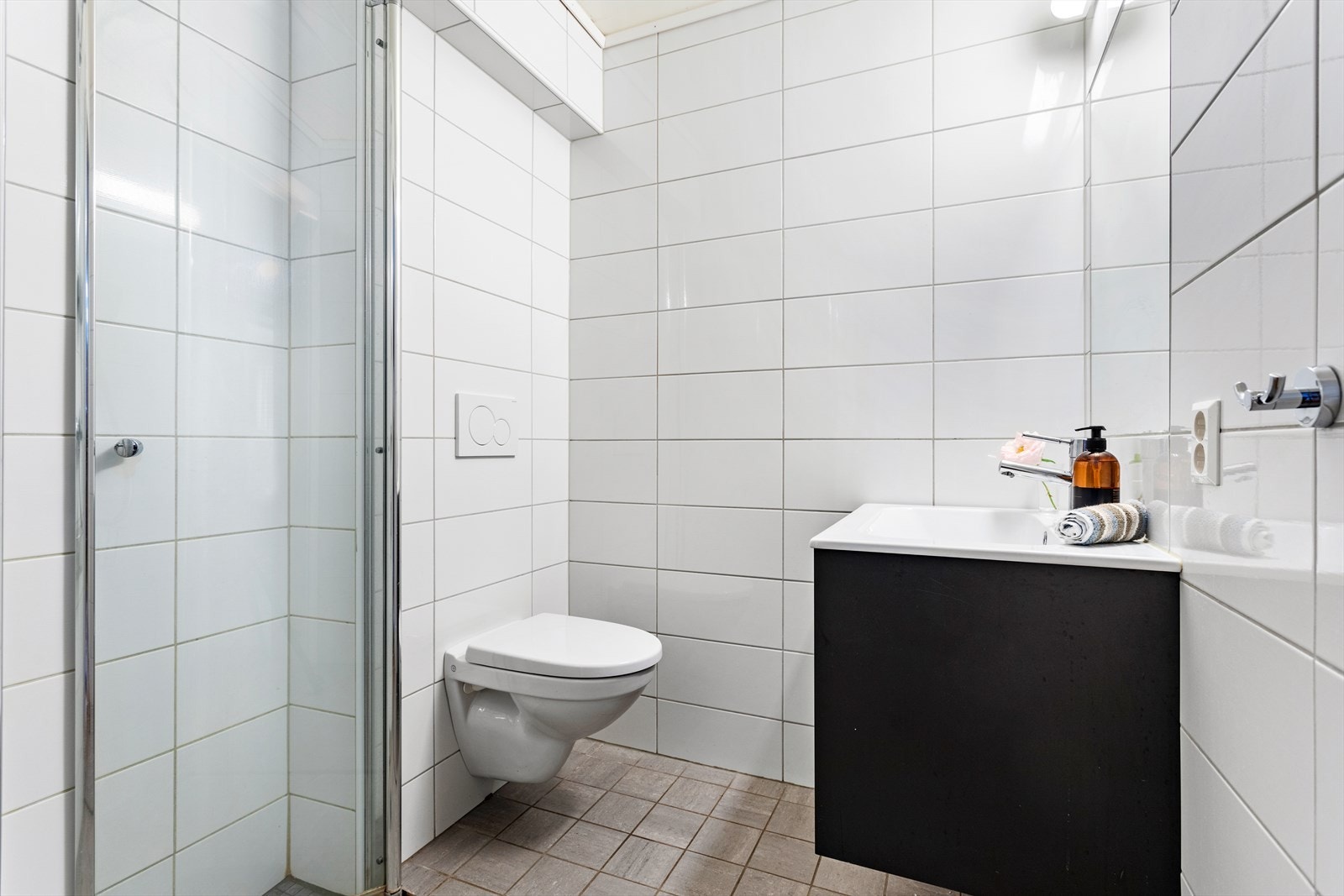 Badet i gang i 1. etasje er innreidd med servant, dusjplass og vegghengt toalett. Veggane er flislagde, medan himlinga er utført med 60 × 120 cm plater. Galleribilde