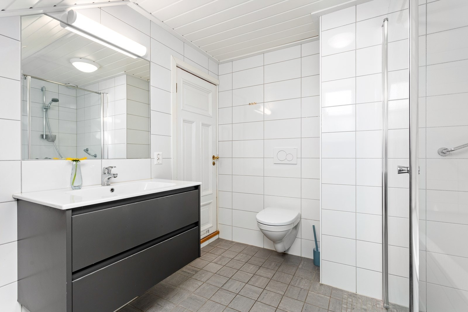 Badet er innreidd med badekar, dusjhjørne, baderomsmøbel med nedfelt servant og vegghengt toalett. Naturleg ventilasjon. Galleribilde