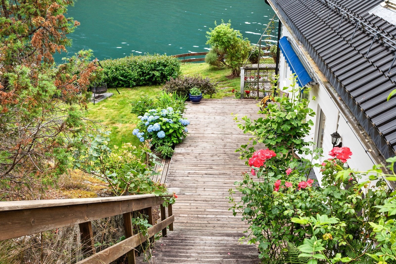 Frå bustaden fører trapp ned til den romslege terrasse og velstelt hage som strekkjer seg mot fjorden. Galleribilde