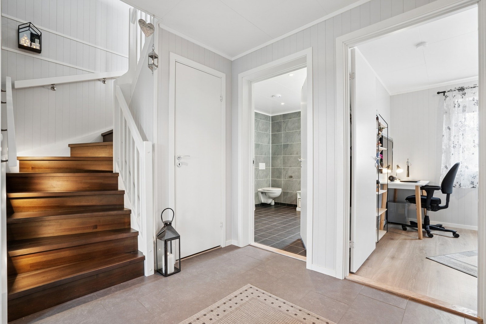 Tretrapp med malte vanger leder opp til stue og kjøkken i andre etasje. Galleribilde