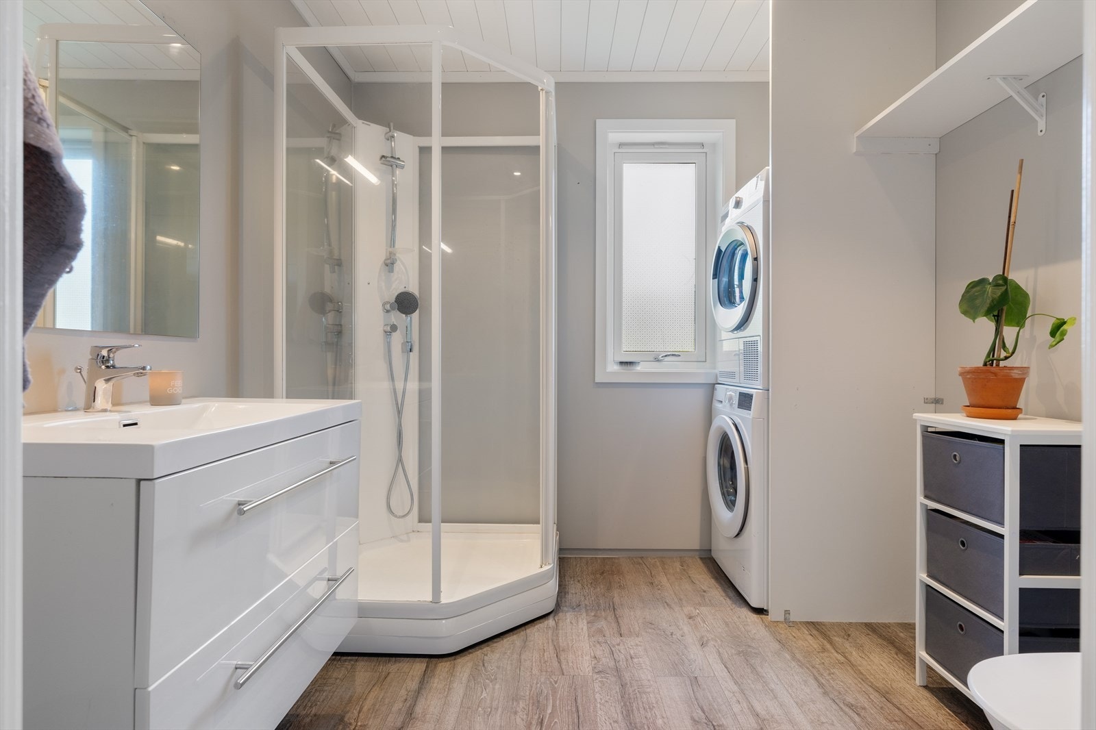 Bad på ca. 5 kvadratmeter - Gulv belagt med klikkvinyl over gulvbelegg, vegger med våtromsmaling og himling av MDF-panel med downlights. Dusjkabinett med integrert blandebatteri og garnityr. Opplegg for vaskemaskin og tørketrommel. Galleribilde