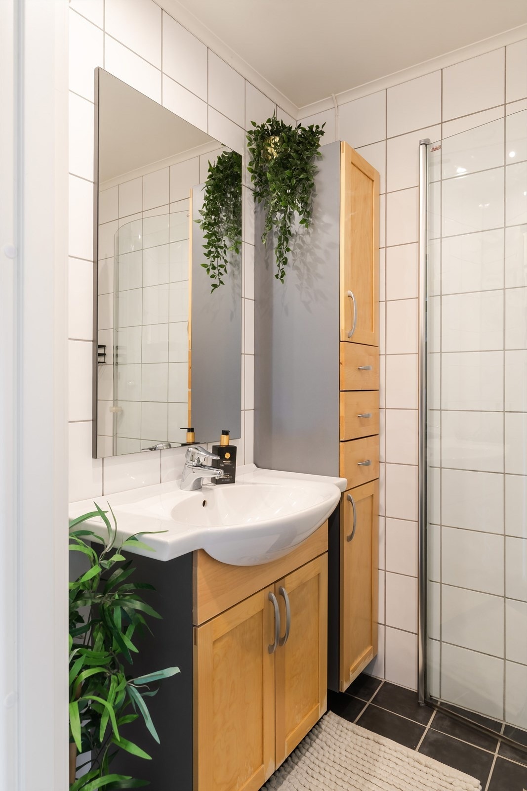 Badet er på ca. 2 m² og har grå fliser på gulv med elektriske varmekabler, lyse fliser på veggene og malt, slett himling. Galleribilde
