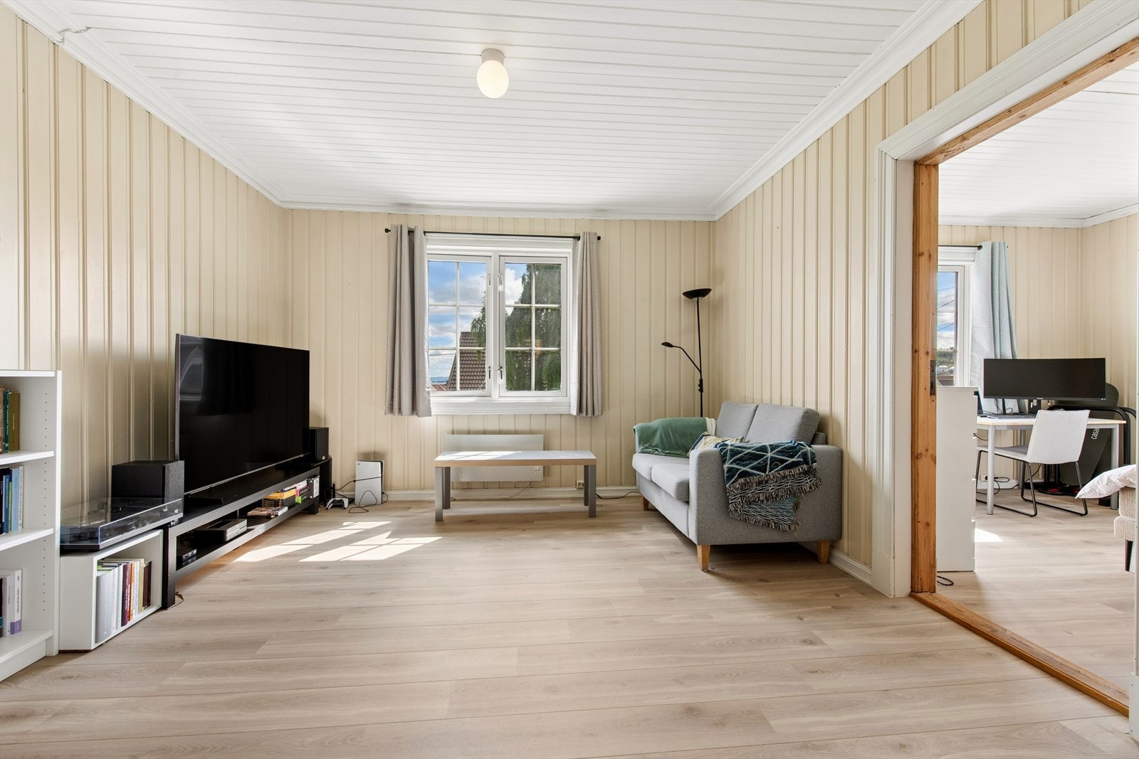 Lys og trivelig stue med gode møbleringsmuligheter. Rommet har laminat på gulvene og malt panel på vegger og i himling. Galleribilde