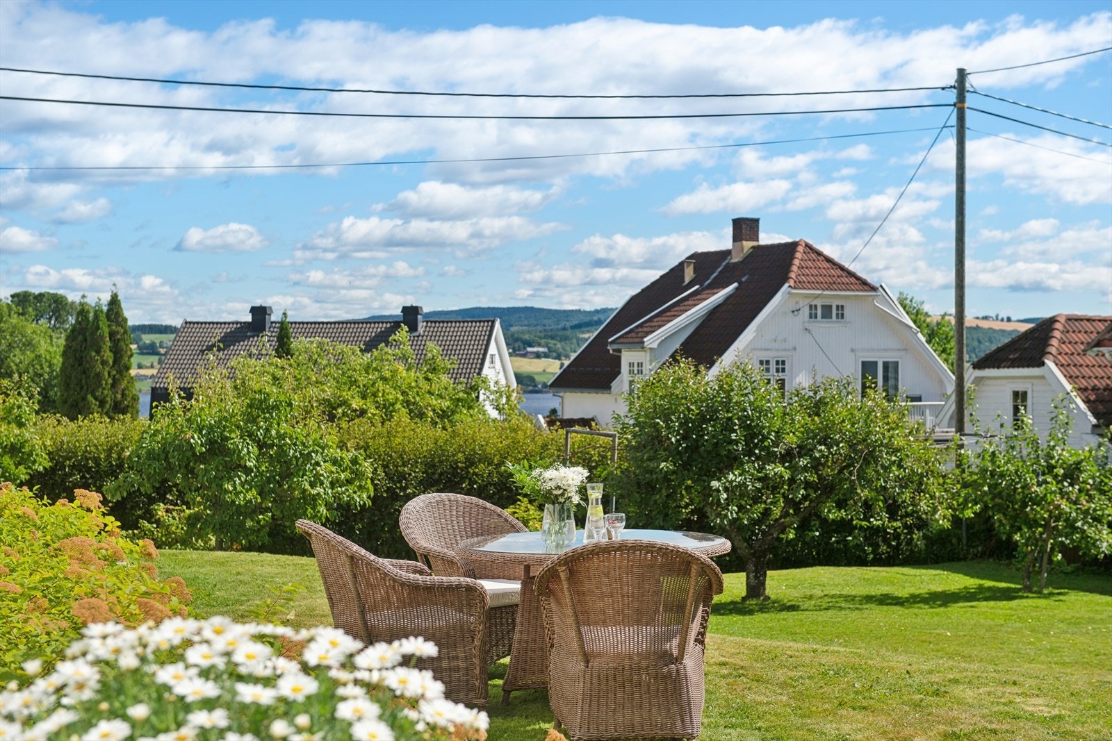 En fredelig uteplass i hagen som er pent opparbeidet med gressplen, hekker, busker og øvrige beplantninger som bidrar til et hyggelig utemiljø. Galleribilde