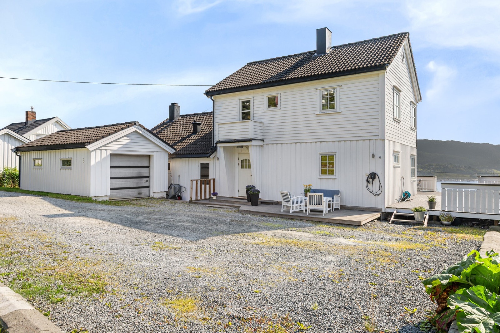 Gruslagt gårdsplass med gode parkeringsmuligheter og garasje. Det er montert elbillader. Galleribilde