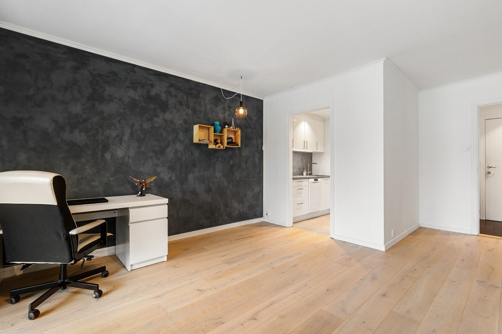Leiligheten har en lys og moderne stue, med fondvegg som gir rommet karakter og bryter med de hvite flatene ellers. Laminatgulvet er lyst og moderne. Galleribilde